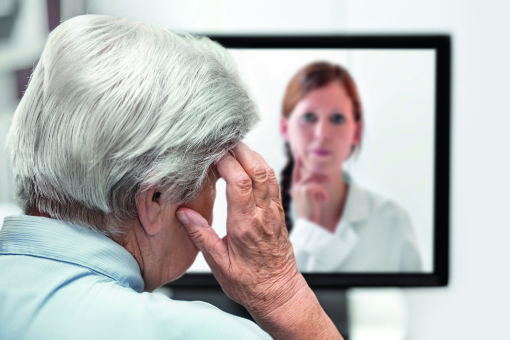 Seniorin mit Kopfschmerzen vor dem Computer