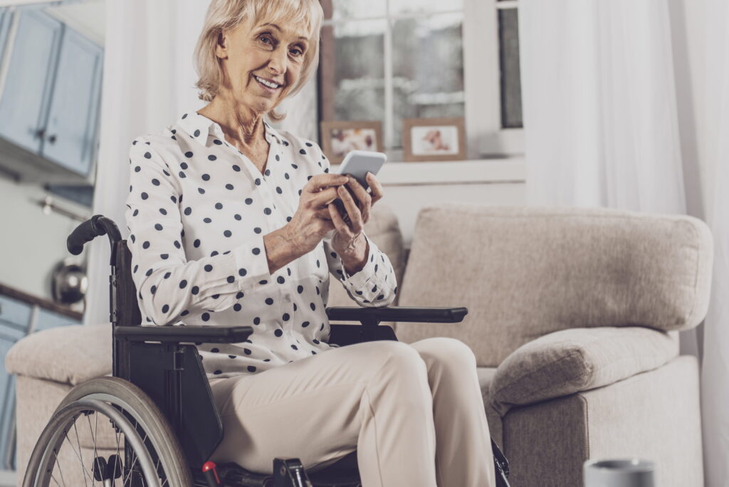 Seniorin mit Smartphone im Rollstuhl; Foto: AdobeStock/Vlacheslav Lakobchuk