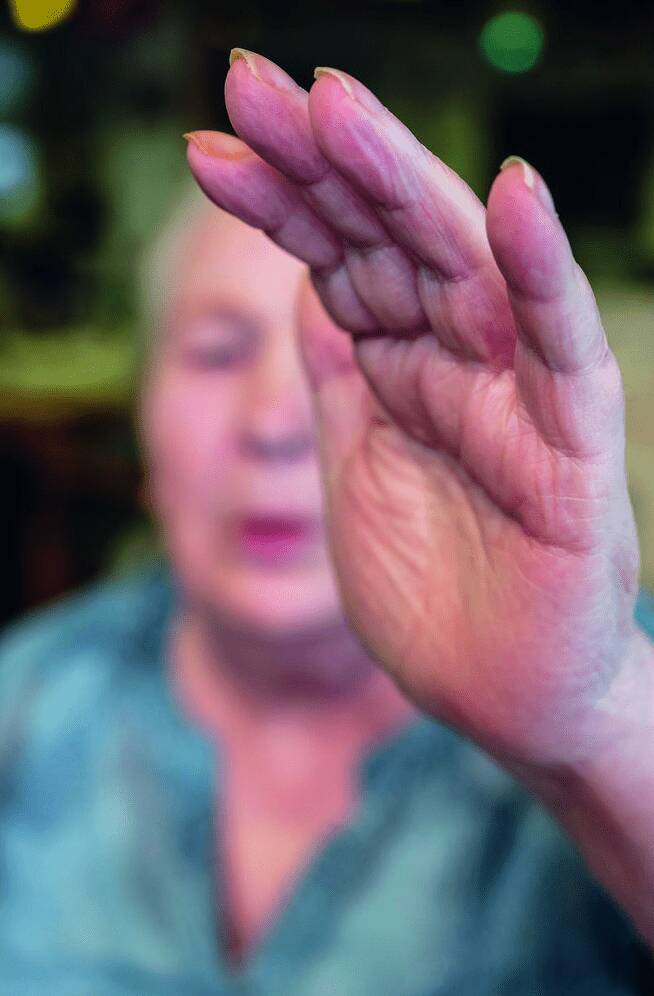 Seniorin hält schützend die Hand vor ihr Gesicht