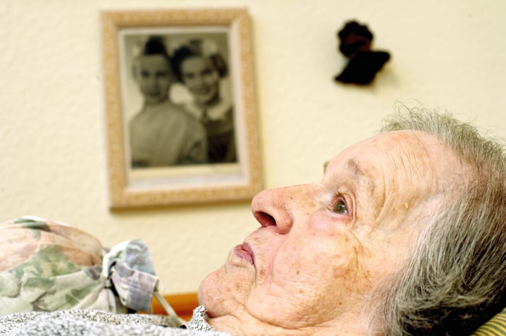 Ältere Dame liegt mit offenen Augen im Bett