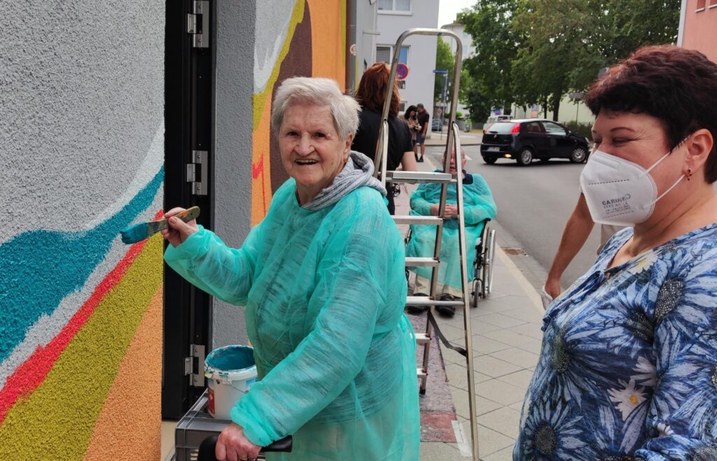 Kunstprojekt: Heimbewohnerin bemalt die Fassade ihres Pflegeheims.