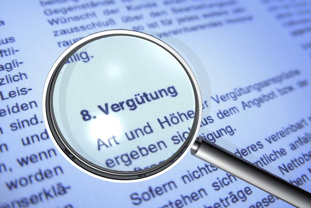 Das Wort Vergütung in einem Schriftstück wird mit einer Lupe vergrößert