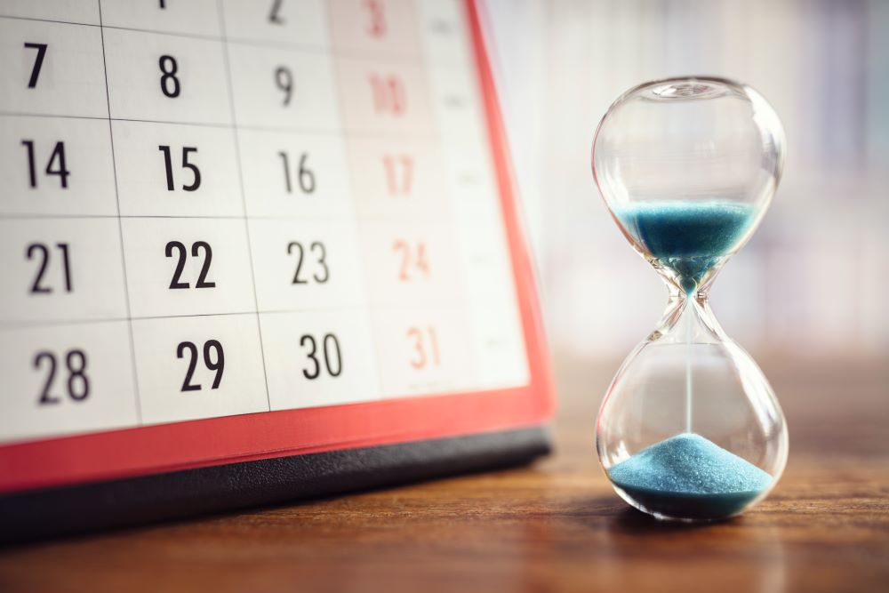 Sanduhr steht vor einem Tischkalender