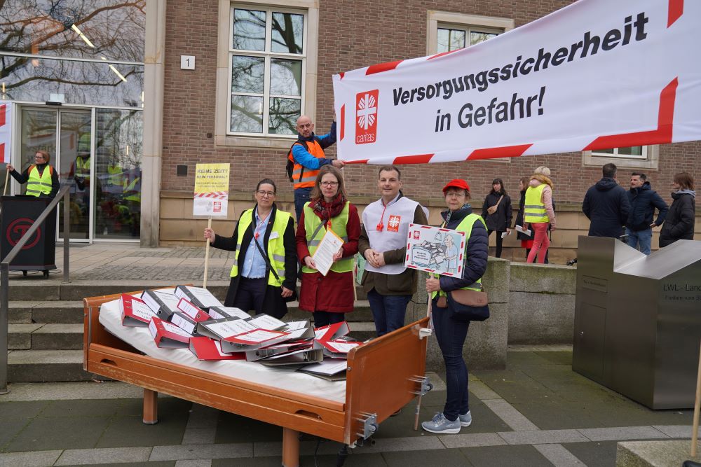Ein mit Aktenordnern gefülltes Pflegebett steht vor einem Gebäude.