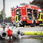 Feuerwehr und Rettungsdienst im Einsatz. Im Vordergrund liegt ein Feuerwehrschlauch.