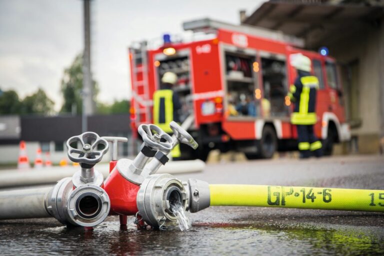 Feuerwehr und Rettungsdienst im Einsatz. Im Vordergrund liegt ein Feuerwehrschlauch.
