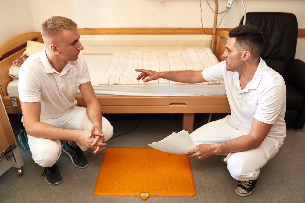 Zwei männliche Pfleger begutachten ein Pflegebett.