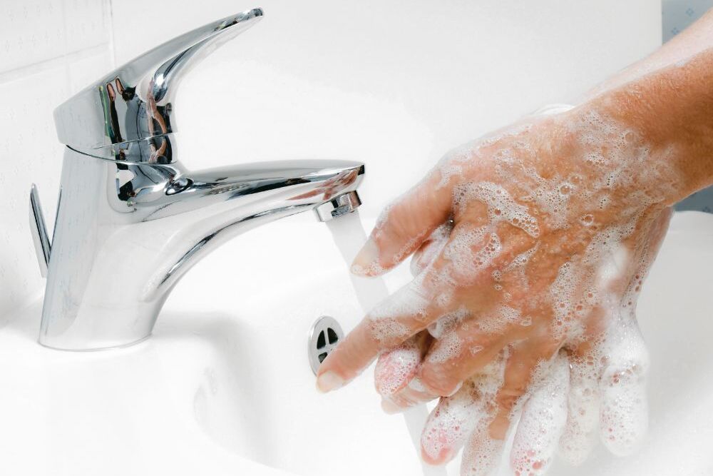 Frau wäscht sich mit fließendem Wasser und Seife die Hände