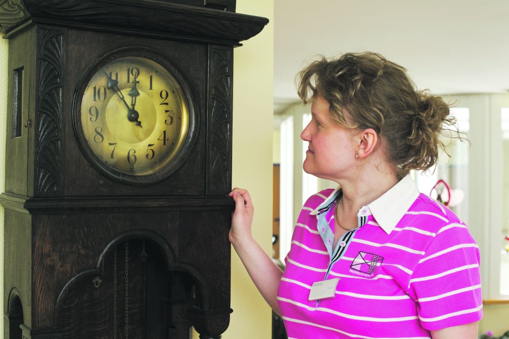 Mitarbeiterin schaut auf eine Uhr
