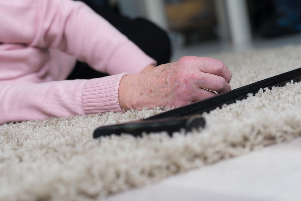 Sturz: Person liegt auf einem Teppich auf dem Boden