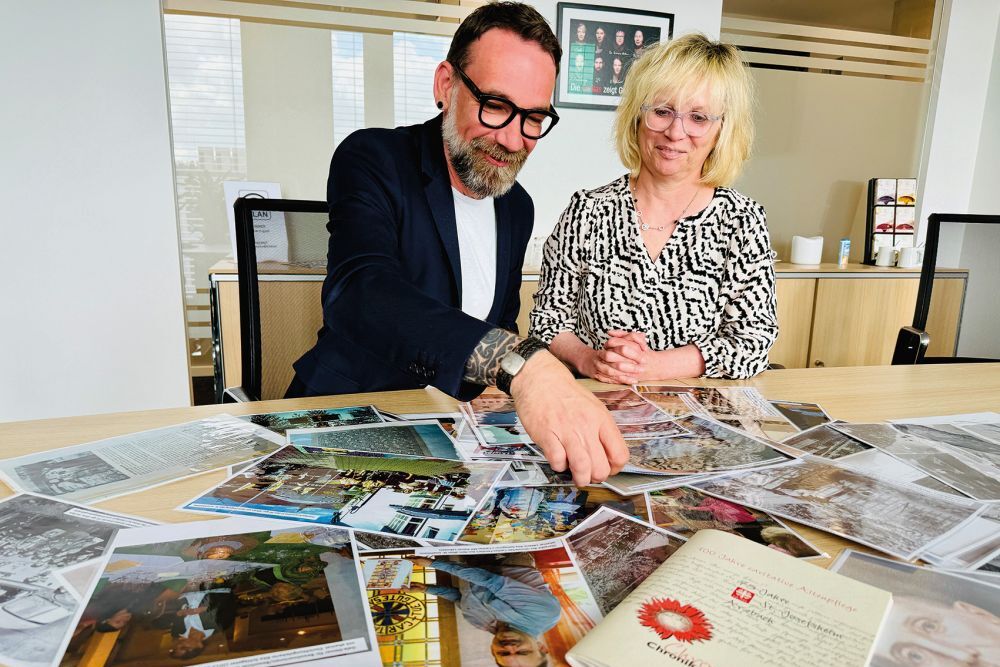 Anja Kohlhaas und Carsten Bachert schauen sich alte Fotos vom Caritas-Altenzentrum St. Josef in Arzbach an, das in diesem Jahr sein 100-jähriges Bestehen feiert.