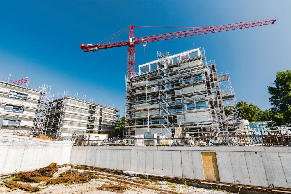 Blick auf eine Baustelle, auf der ein Hochhaus entsteht. Im Vordergrund steht ein Kran.