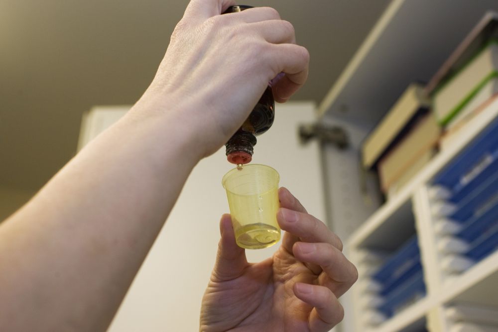Aus einer Tropfflasche werden Tropfen in einen Bescher gegeben.