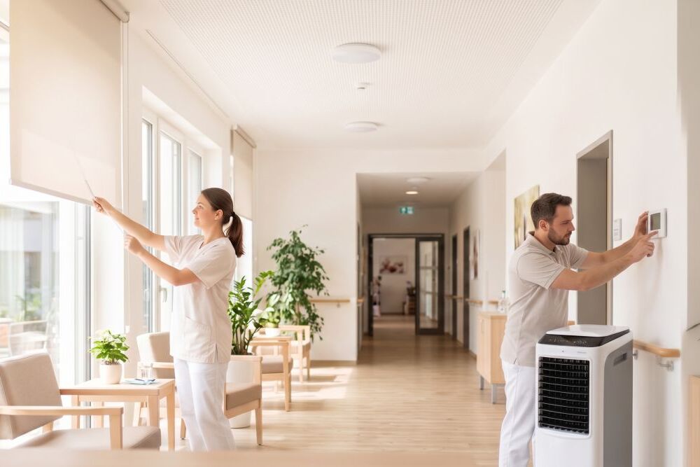 Pflegemitarbeitende stehen in einem Raum und bedienen ein Rollo und eine Klimaanlage