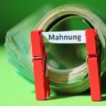 Ein Schilchen, von zwei Klammern gehalten, auf dem das Wort "Mahnung" steht.