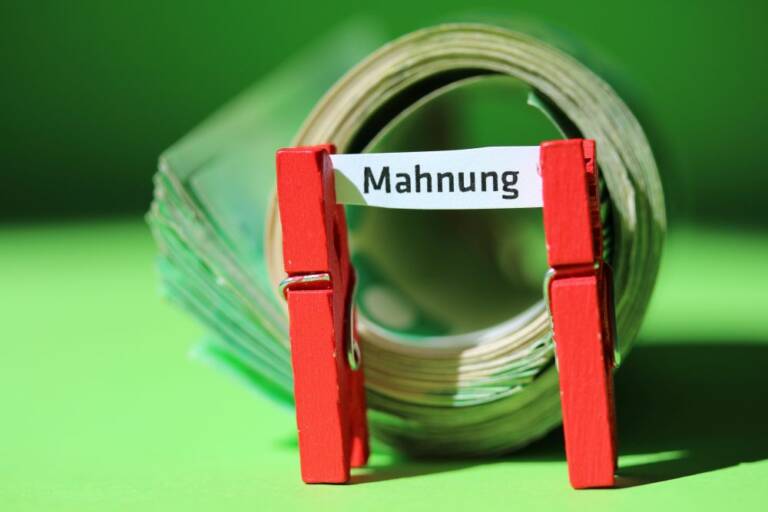 Ein Schilchen, von zwei Klammern gehalten, auf dem das Wort "Mahnung" steht.