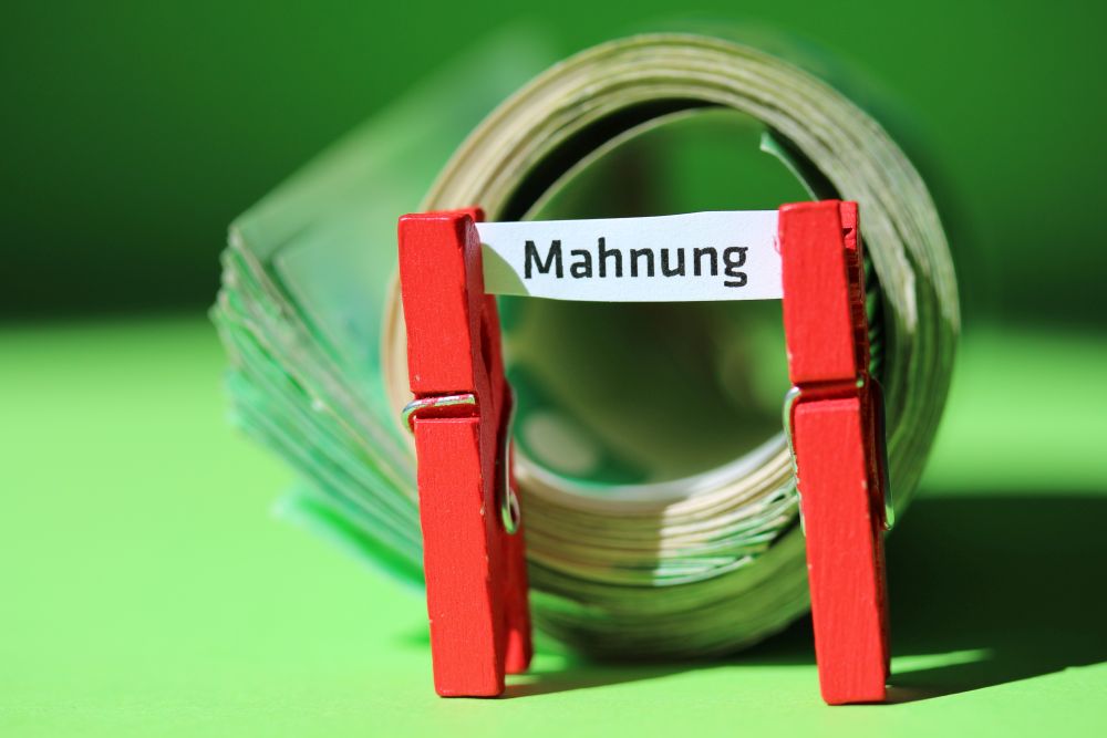 Ein Schilchen, von zwei Klammern gehalten, auf dem das Wort "Mahnung" steht.