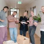 Junge Menschen stehen mit Umzugskarton in einem Flur.