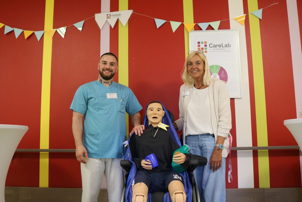 Die Azubistation in Friedehorst: Nicole Gries-Lamprecht, einrichtungsübergreifende Praxisanleiterin (rechts) und Saba Guliashvili, Auszubildender zur Pflegefachkraft mit Übungspuppe „Gerry“.