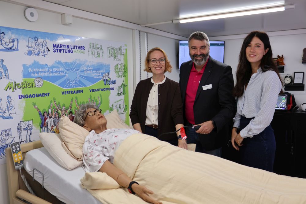 Jasmin Modis und Thorsten Hitzel (Martin Luther Stiftung Hanau) sowie Salomé Eggler (Google) im Mobilen Skills Lab (v.l.n.r.). Im Vordergrund ist die Pflege-Simulationspuppe zu sehen.