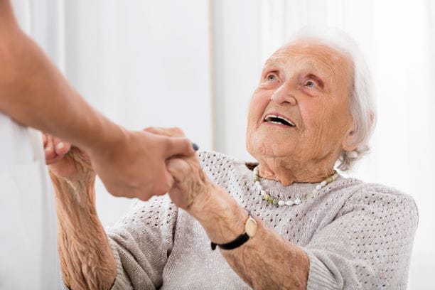 Ältere Dame fast eine Person bei den Händen.